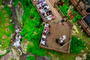 Guests gathered on wooden decks overlooking waterfalls during an outdoor wedding at Weddings Over Waterfalls, a unique nature-focused wedding venue in NC.